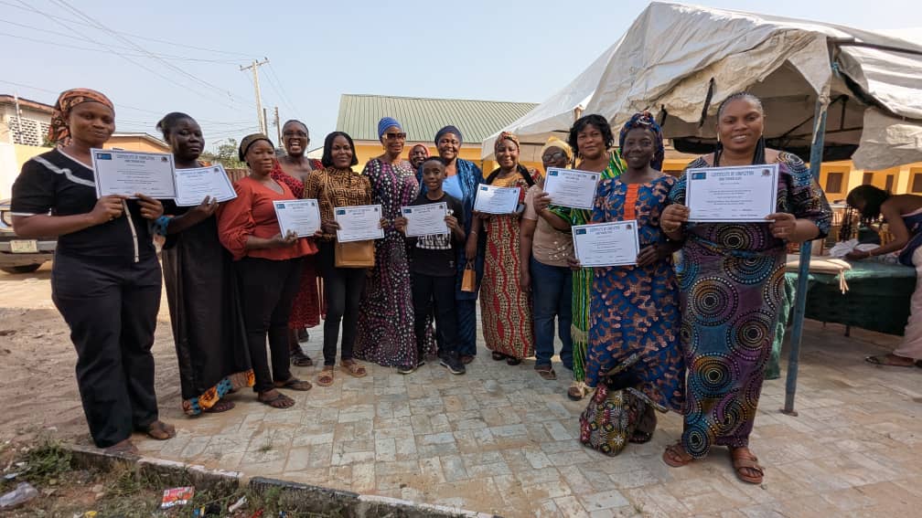 "Participants displaying their Adire creations, and  certificates of participation at the Ajowa Funfair."