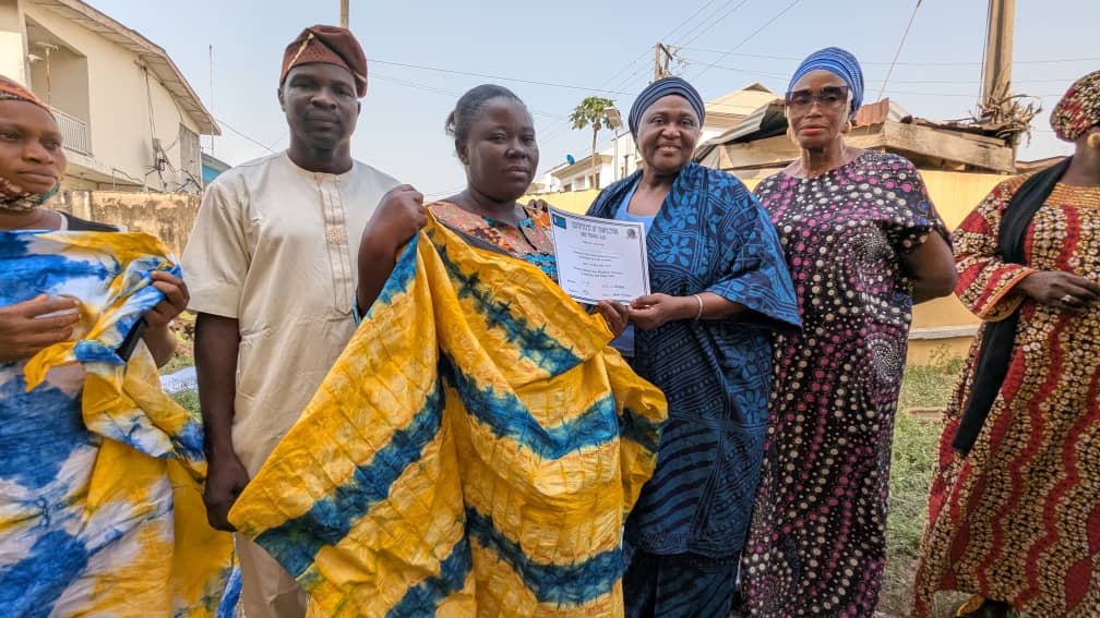 "Participants displaying their Adire creations, and  certificates of participation at the Ajowa Funfair."