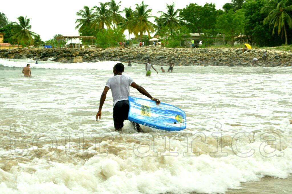 Visitors having fun at Tarkwa Bay Beach in Lagos with palm trees and Atlantic Ocean views. Tour Africa Magazine
